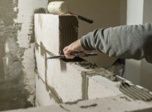 a male builder puts a wall of foam concrete blocks, he spreads a mortar for masonry with a spatula.