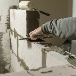 a male builder puts a wall of foam concrete blocks, he spreads a mortar for masonry with a spatula.