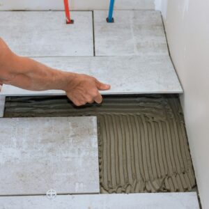 Home construction working with placing ceramic floor tiles on adhesive