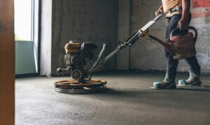 Worker performing and polishing sand and cement screed floor