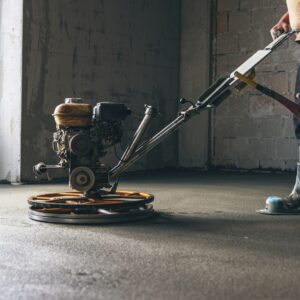 Worker performing and polishing sand and cement screed floor