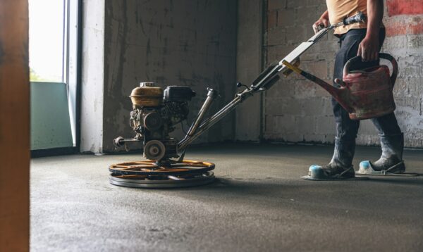 Worker performing and polishing sand and cement screed floor